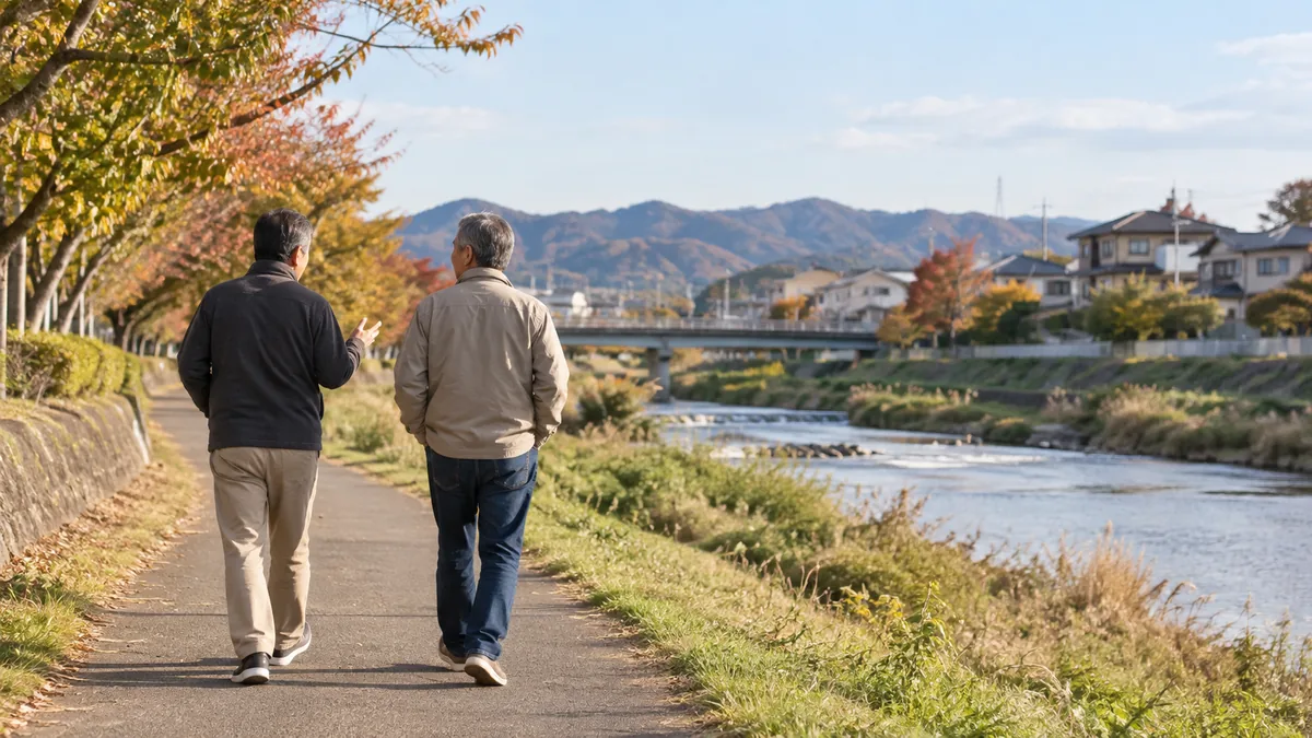 川沿いの遊歩道を、同年代の知人と並んで散歩する50代男性の後ろ姿